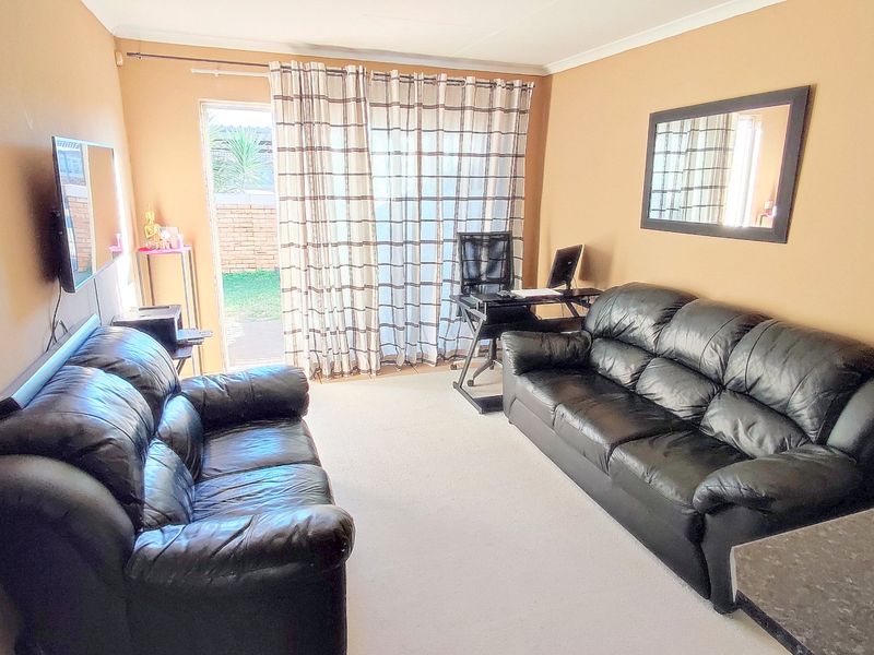 A functional living room featuring carpeted flooring and a sliding glass door providing access to the outdoor area.