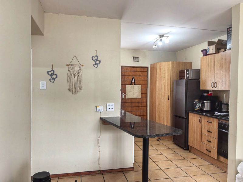 Functional kitchen featuring wooden cabinetry, granite breakfast bar, tiled flooring, and built-in oven, offering a practical layout for daily meal preparation.