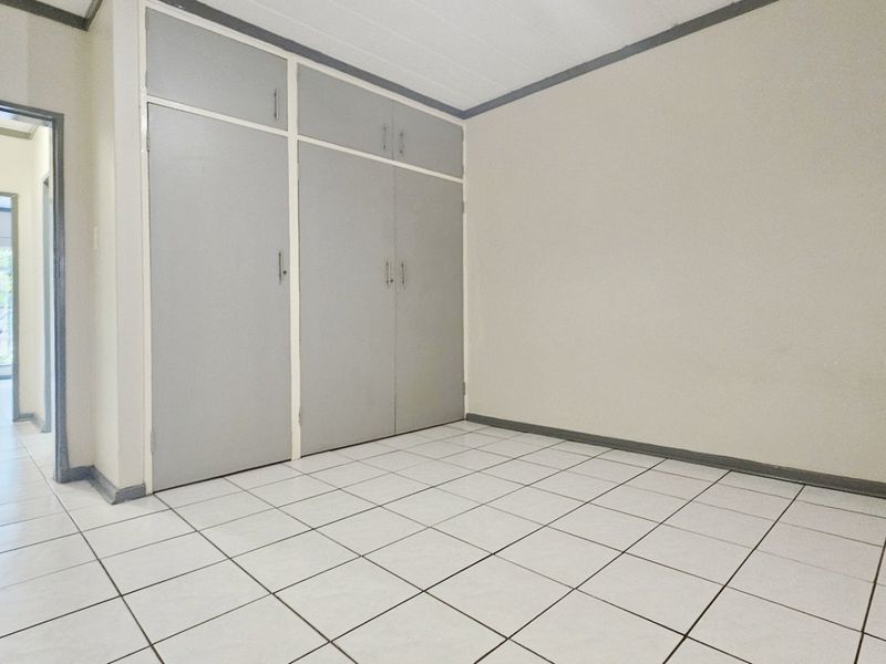 An empty bedroom featuring tiled flooring and built-in cupboards, offering a neutral canvas for personalization.