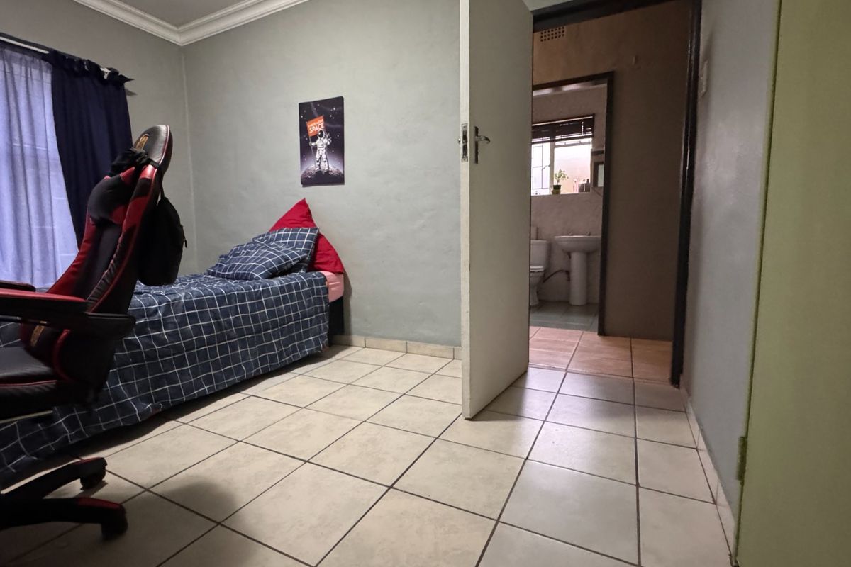 A bedroom featuring tiled flooring and cornice detailing, with direct access to an adjacent bathroom.