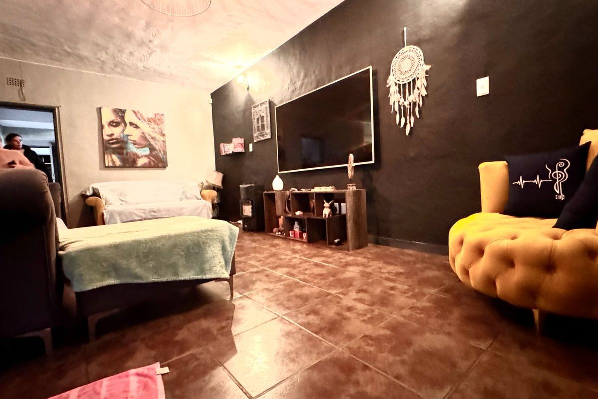 A living room featuring dark accent wall, tiled flooring, and textured ceiling, offering a blank canvas for potential interior design updates.