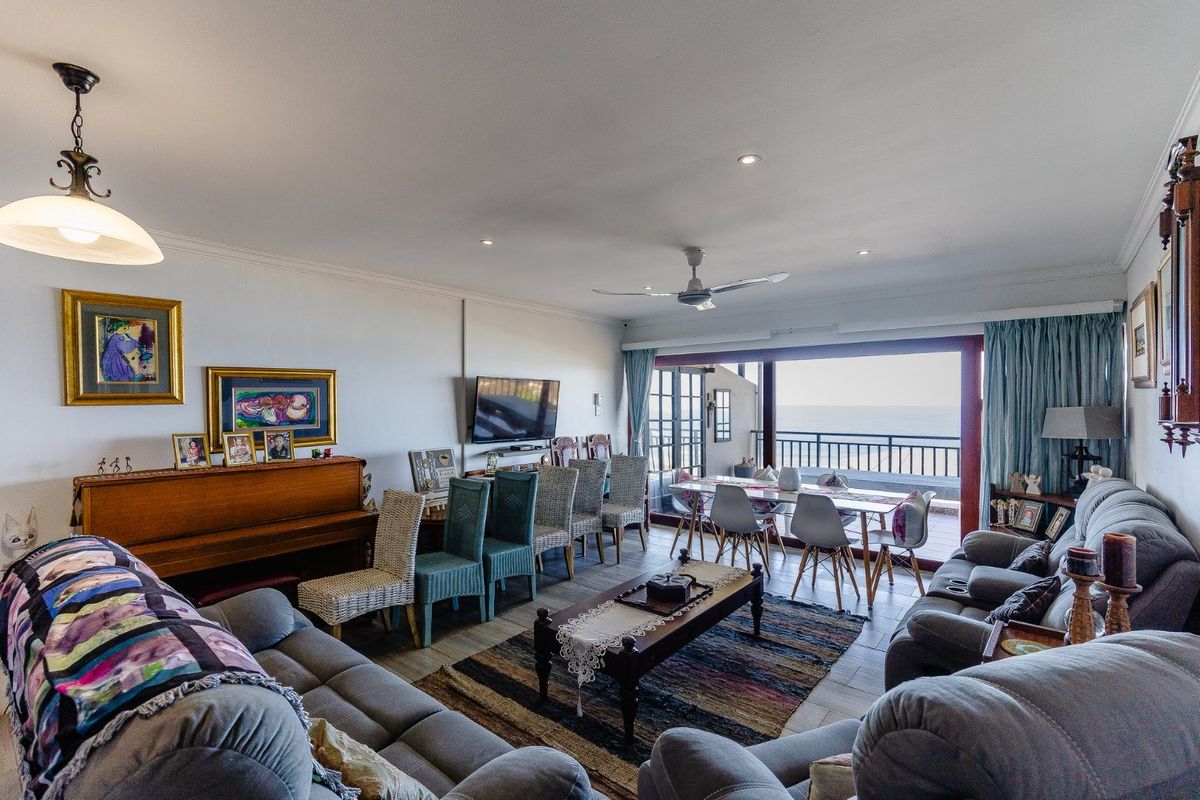 Spacious living area featuring tiled floors, recessed lighting, and large sliding glass doors opening onto a balcony with ocean views.