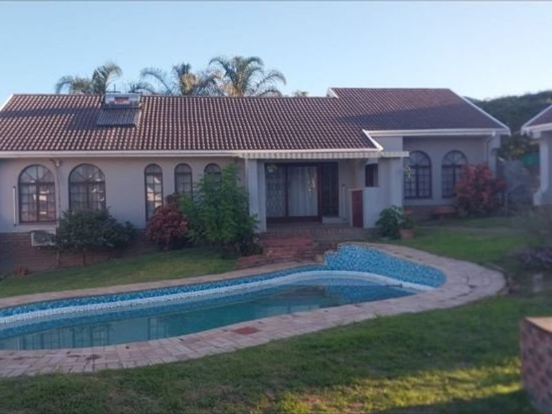 Rear view of the house featuring a swimming pool, landscaped garden, and a tiled roof with an integrated solar water heating system.