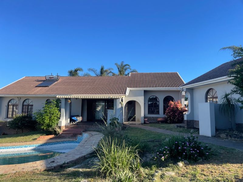 Rear view of the house featuring a tiled roof with solar water heater, a swimming pool, and a covered patio area.