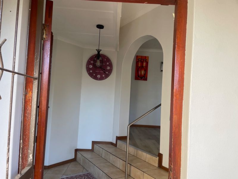 Entrance foyer featuring a tiled staircase with a metal handrail, leading through an arched doorway into the home interior.