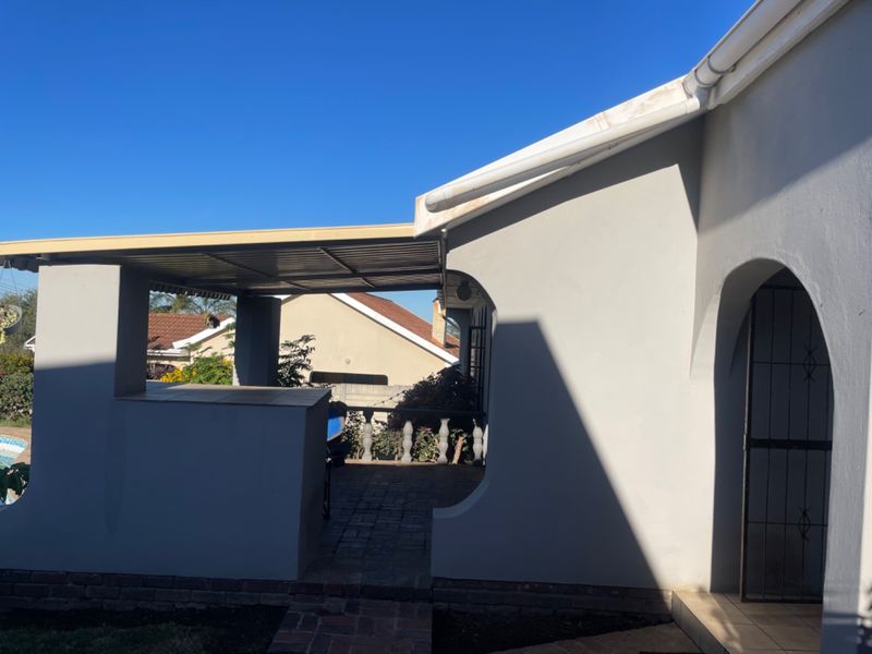 A covered outdoor patio area featuring brick paving, an arched entrance, and a built-in balustrade, providing a functional space for outdoor living.