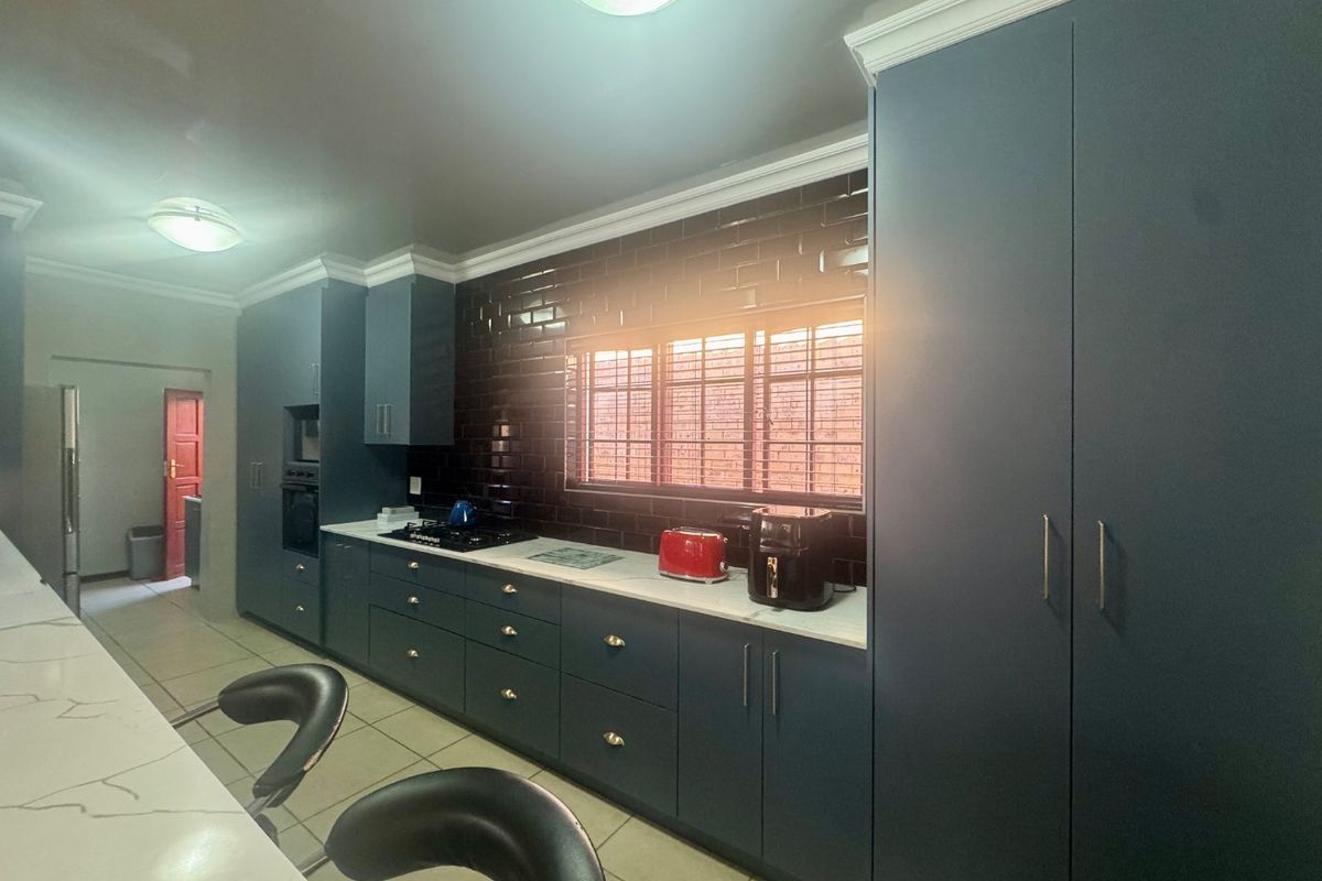 Modern kitchen featuring dark blue cabinetry, stone countertops, a subway tile backsplash, and integrated appliances with ample storage space.