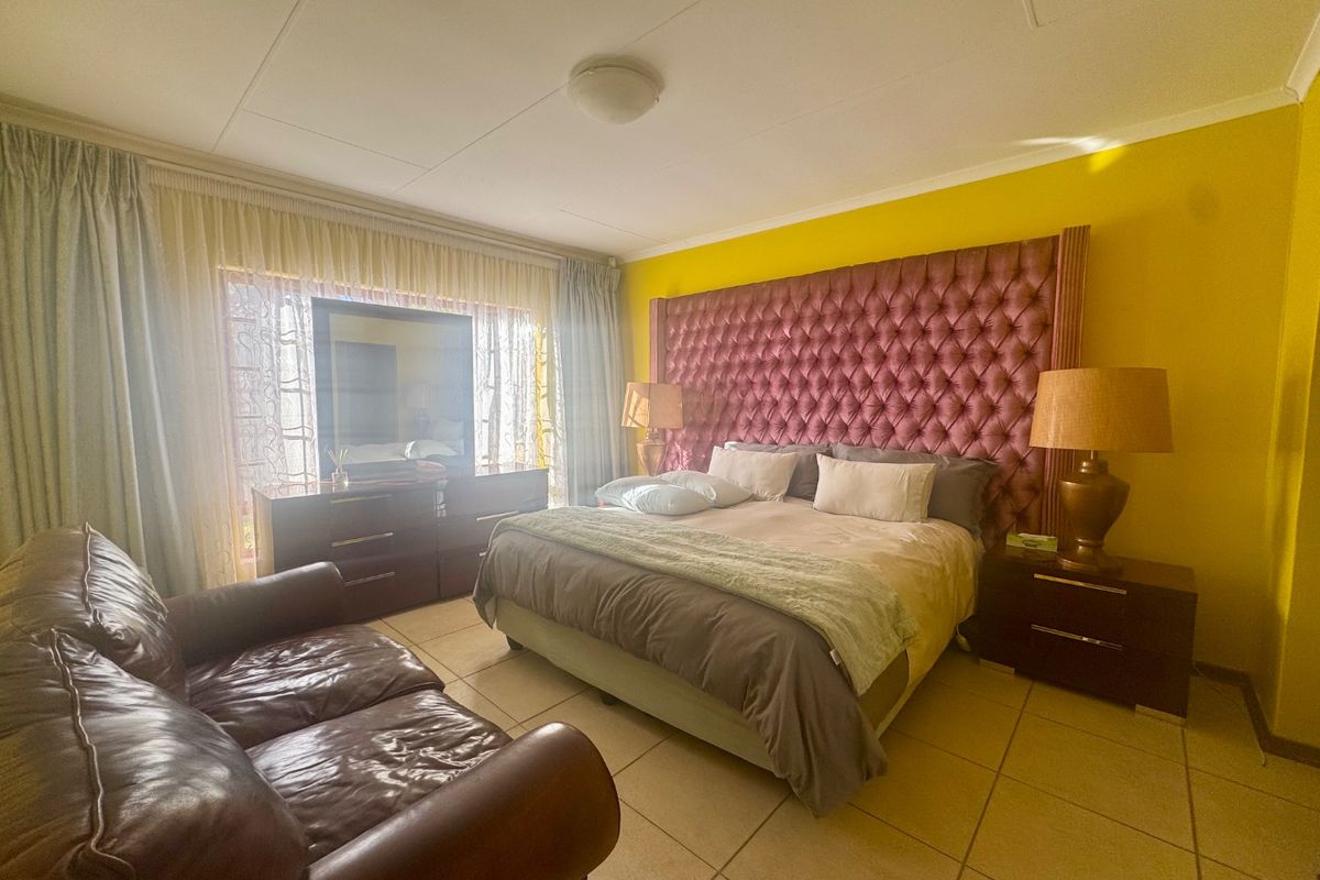 Spacious bedroom featuring tiled flooring and a large window with curtain tracks, providing a functional layout for a primary suite.