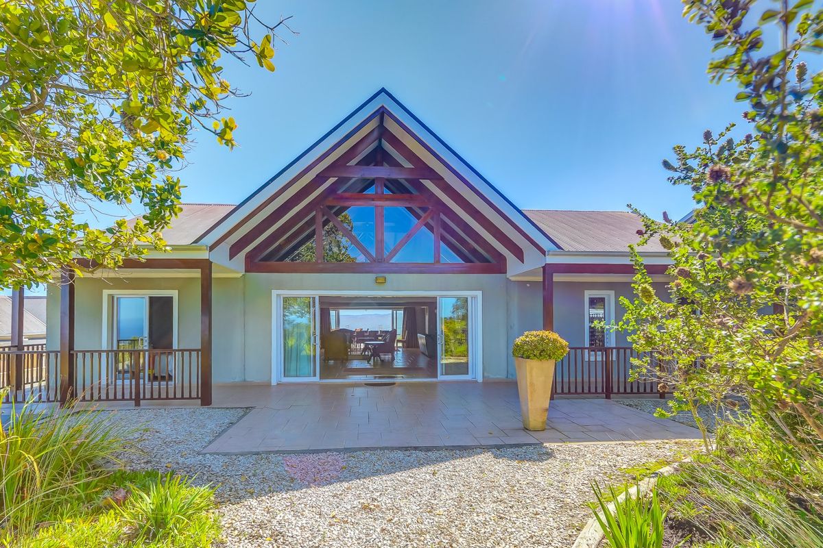 Rear elevation featuring a prominent timber gable, tiled patio area, and large sliding glass doors providing seamless indoor-outdoor flow.