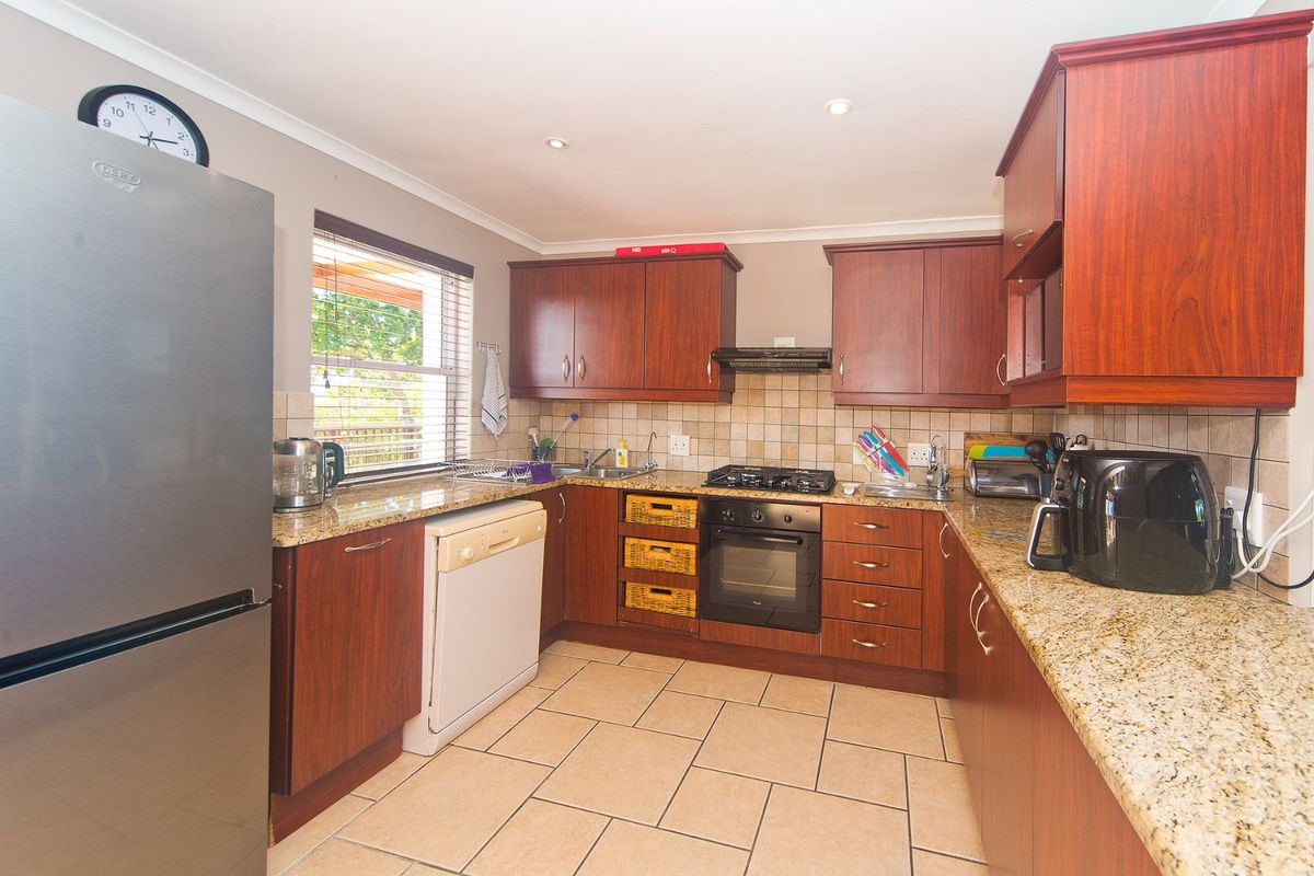 A functional kitchen featuring wooden cabinetry, granite countertops, a built-in oven with gas hob, and tiled flooring.