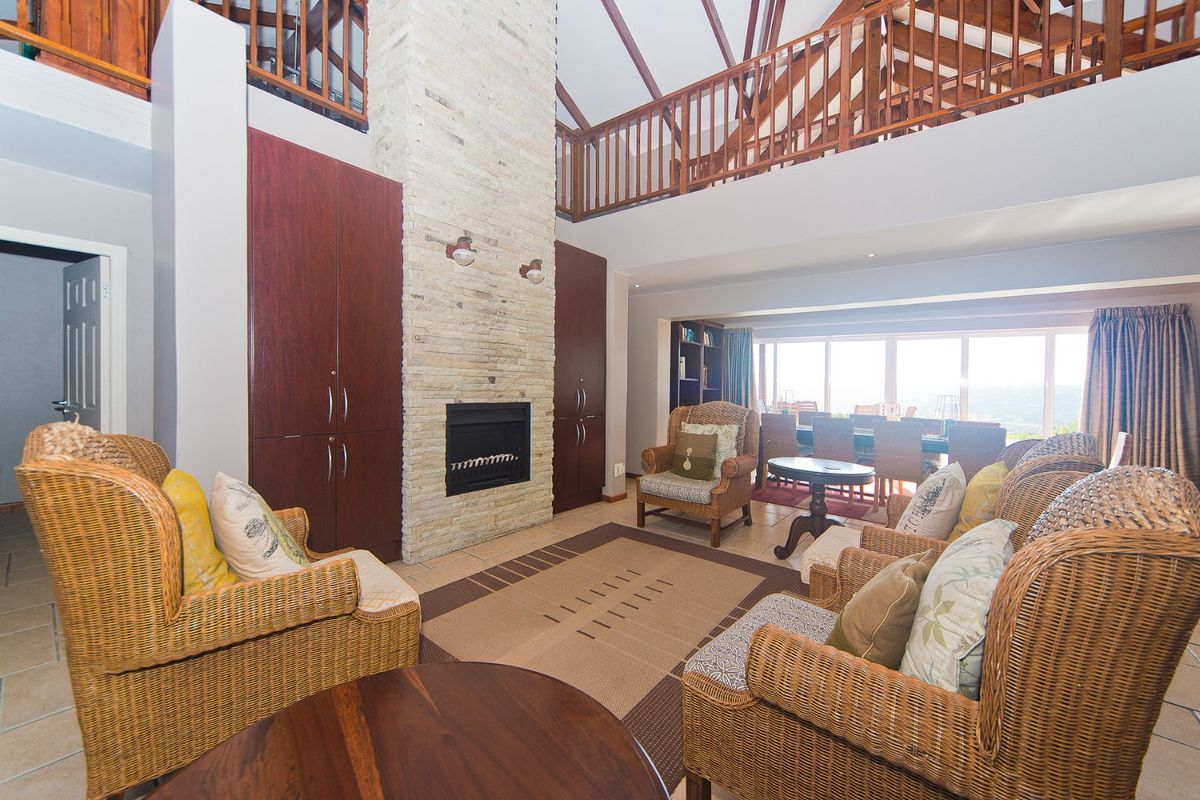 Spacious living room featuring a prominent stone fireplace, vaulted ceilings with mezzanine level, and large windows providing ample natural light.