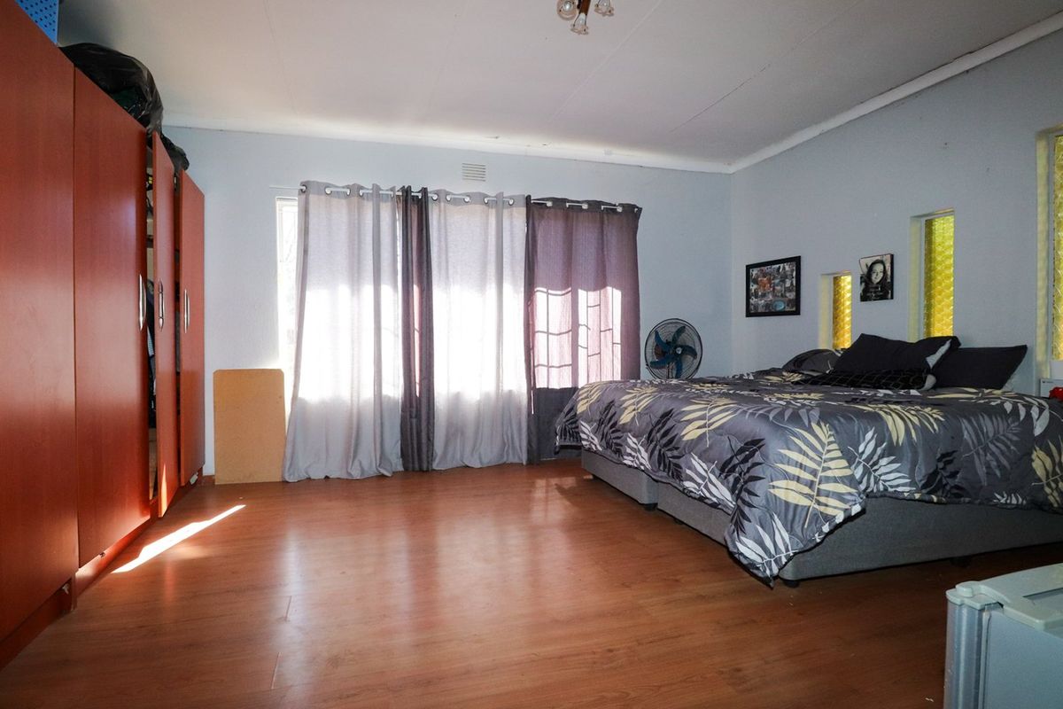 Spacious bedroom featuring laminate flooring and a large built-in wardrobe, offering a functional layout with natural light.