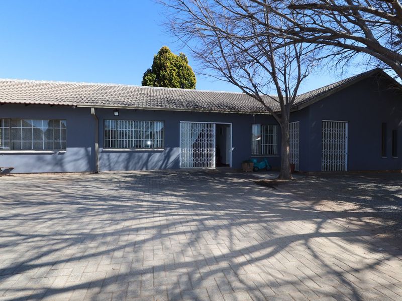 Front exterior view of the house featuring a paved driveway, security gates, and tiled roof.