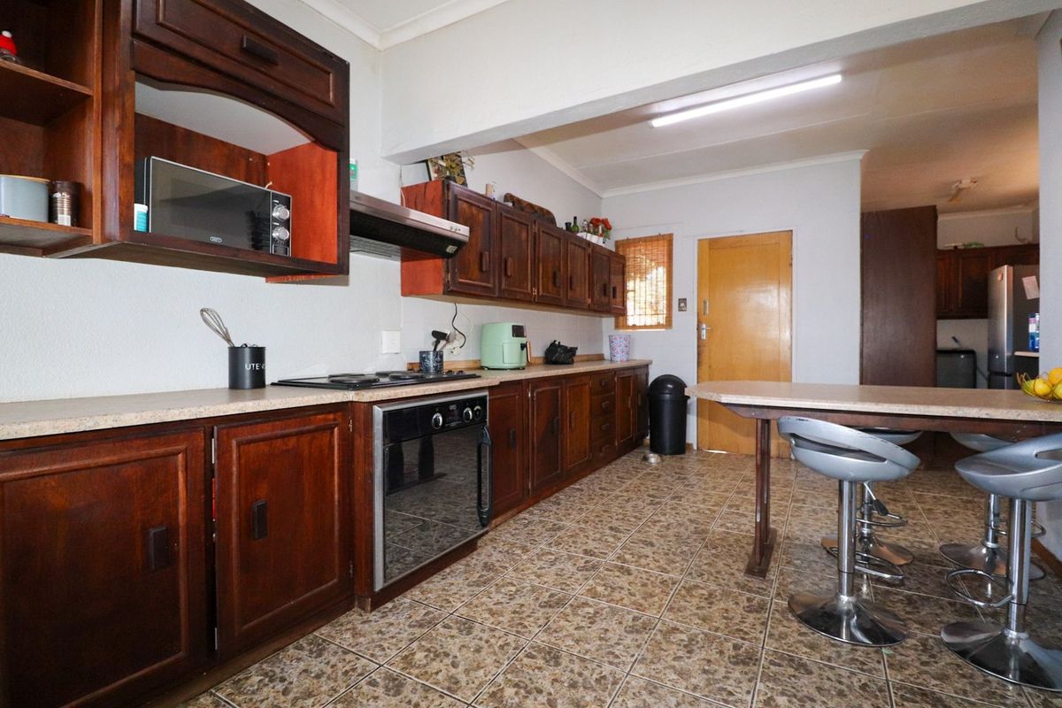 A functional kitchen featuring dark wood cabinetry, laminate countertops, and integrated cooking appliances with tiled flooring throughout.
