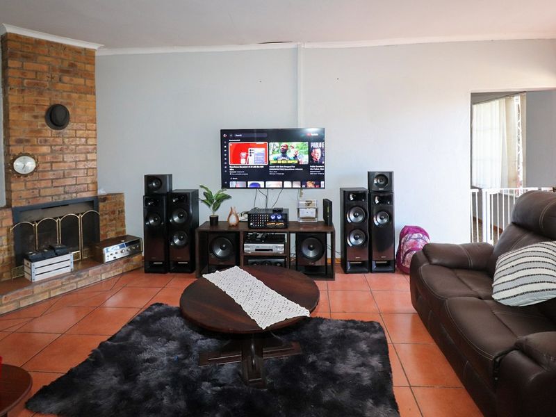 A living room featuring a prominent brick fireplace and tiled flooring, offering a functional space for relaxation and entertainment.