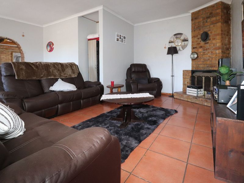 A living room featuring terracotta floor tiles and a prominent brick fireplace, offering a warm and traditional foundation for interior updates.