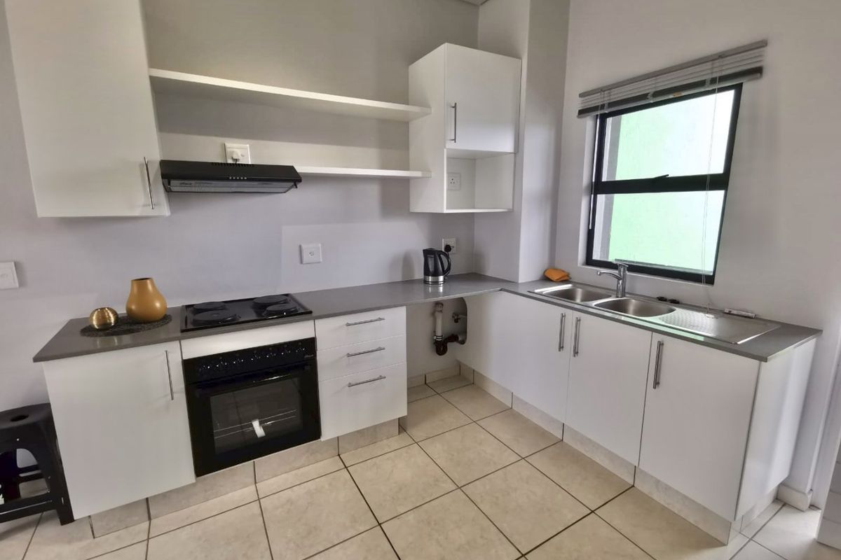 A functional kitchen featuring white cabinetry, stone countertops, a built-in oven with hob, and a double stainless steel sink.