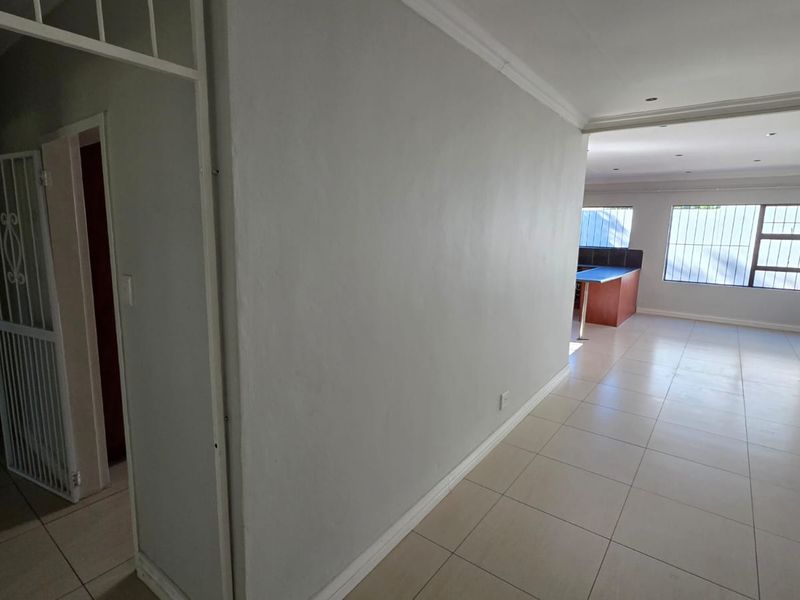 Spacious open-plan living area featuring neutral tiled flooring, recessed lighting, and a functional kitchen layout, offering a blank canvas for interior design.