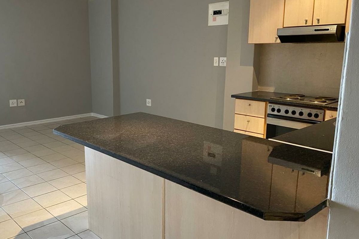 Open plan living area featuring a kitchen with granite countertops, built-in cabinetry, and an integrated electric stove, finished with neutral tiled flooring.