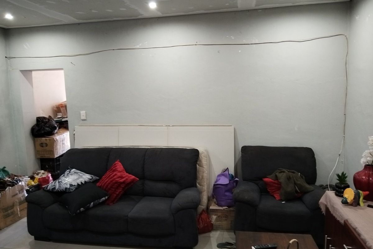 Living room area featuring tiled flooring and recessed lighting, currently requiring ceiling finishing and electrical cable management.