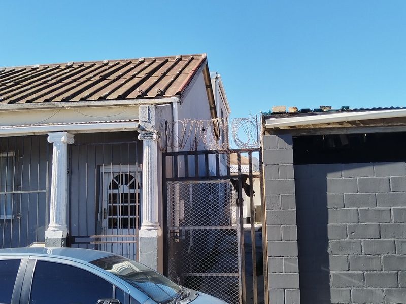 Front facade of the property featuring a security gate with razor wire, decorative columns, and a tiled roof.
