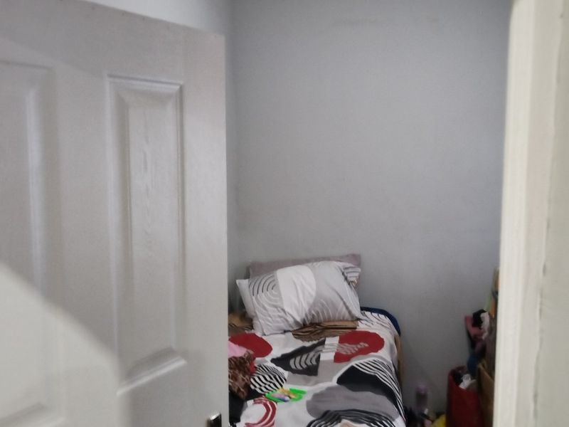A view through a doorway into a compact bedroom featuring a standard panel door and basic ceiling lighting.