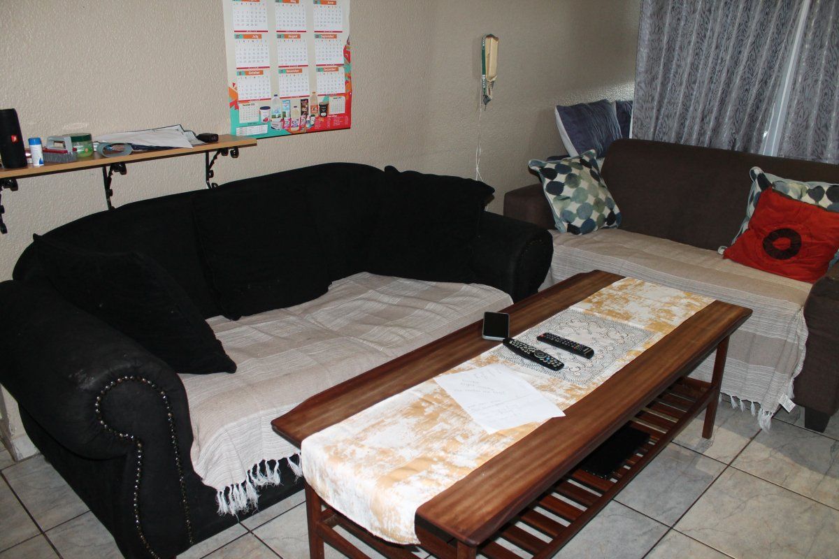 A living room area featuring tiled flooring and a wall-mounted intercom system.