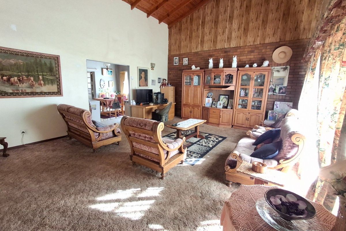 Spacious living room featuring a high vaulted timber ceiling, exposed brick feature wall, and warm wood paneling, offering a classic and cozy atmosphere.