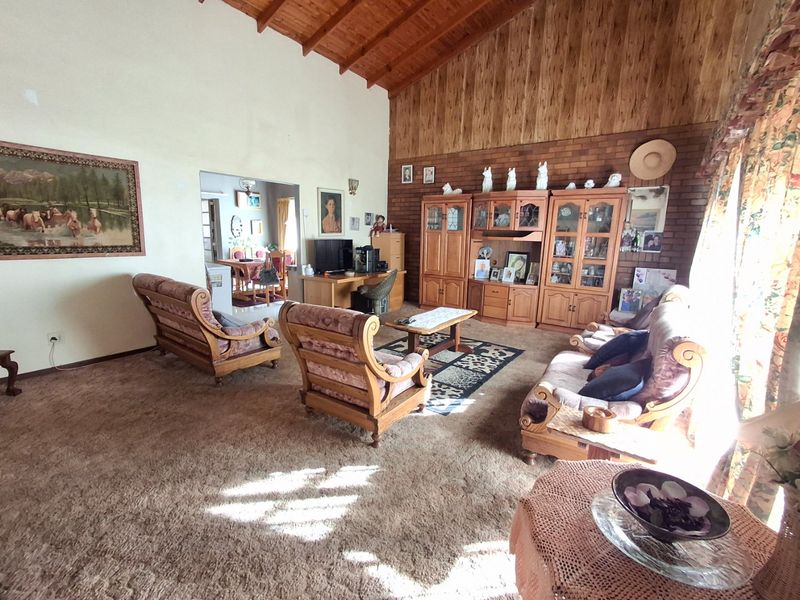 Spacious living room featuring a high vaulted timber ceiling, exposed brick feature wall, and warm wood paneling, offering a classic and cozy atmosphere.