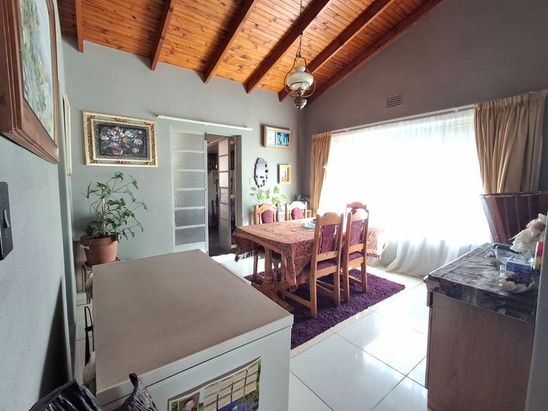 Dining room featuring a high exposed timber rafter ceiling, tiled flooring, and natural light through a large window.