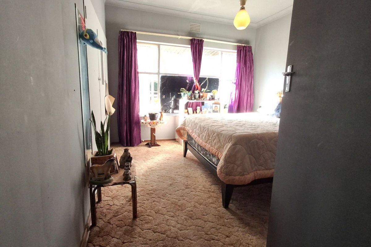 A bedroom featuring large windows for natural light, carpeted flooring, and a central ceiling light fixture, offering a functional space ready for updates.