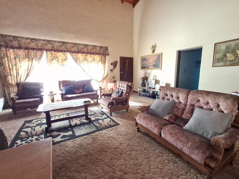 Spacious living room featuring a high vaulted ceiling and wall-to-wall carpeting, offering a generous layout with ample natural light.