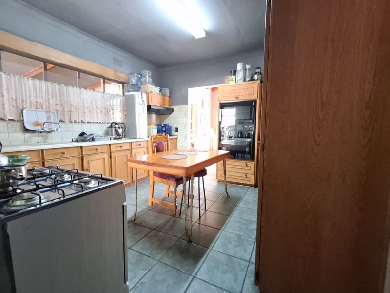 A dated kitchen featuring wooden cabinetry, tiled flooring, a gas stove, and a built-in oven, offering potential for a modern renovation.