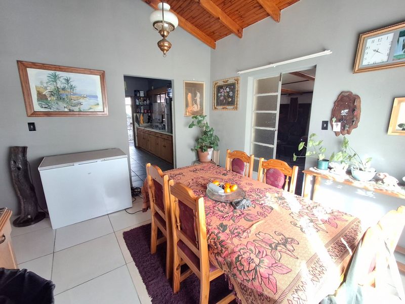 Dining area featuring exposed timber ceiling beams, tiled flooring, and direct access to the kitchen and adjacent living spaces.