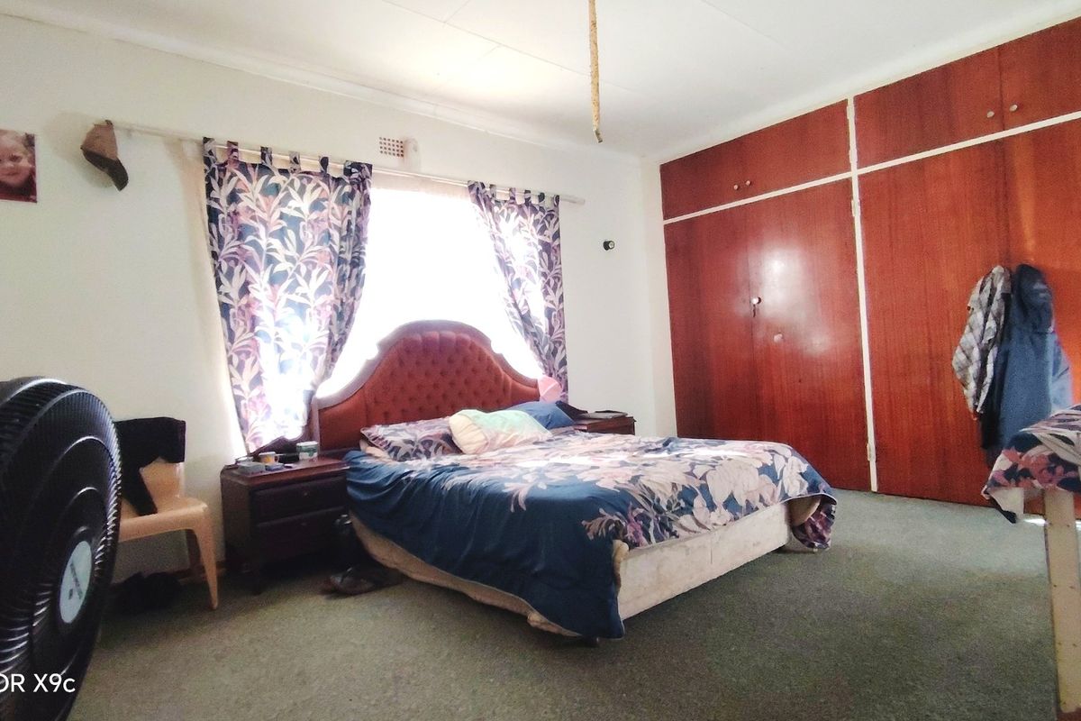 A bedroom featuring built-in wooden cupboards and carpeted flooring, offering a functional space with potential for modernization.