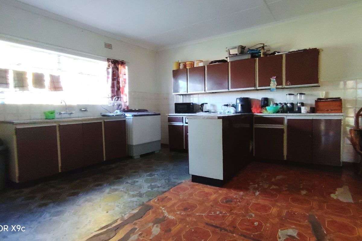 A dated kitchen featuring original cabinetry, laminate countertops, and a double basin sink, requiring modernization of finishes and flooring to improve functionality and aesthetic appeal.