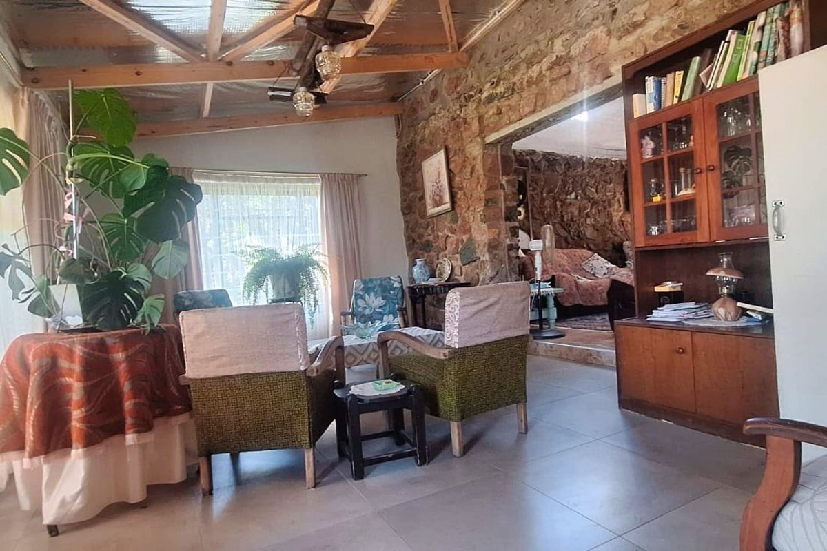 Rustic living area featuring exposed stone walls, timber beam ceiling, and tiled flooring, offering a warm and character-filled atmosphere.