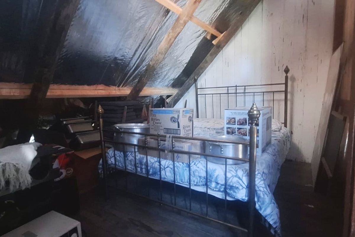 Attic-style bedroom featuring exposed timber rafters and reflective insulation, offering a rustic space with potential for renovation and improved interior finishes.