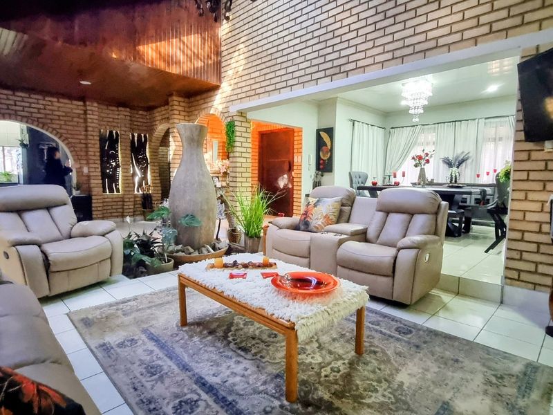 Spacious open-plan living and dining area featuring exposed brick walls, vaulted timber ceilings, and tiled flooring with arched architectural details.