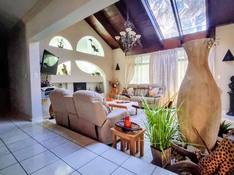 Spacious living room featuring a vaulted timber ceiling with skylights, tiled flooring, and unique built-in arched wall niches surrounding a fireplace.
