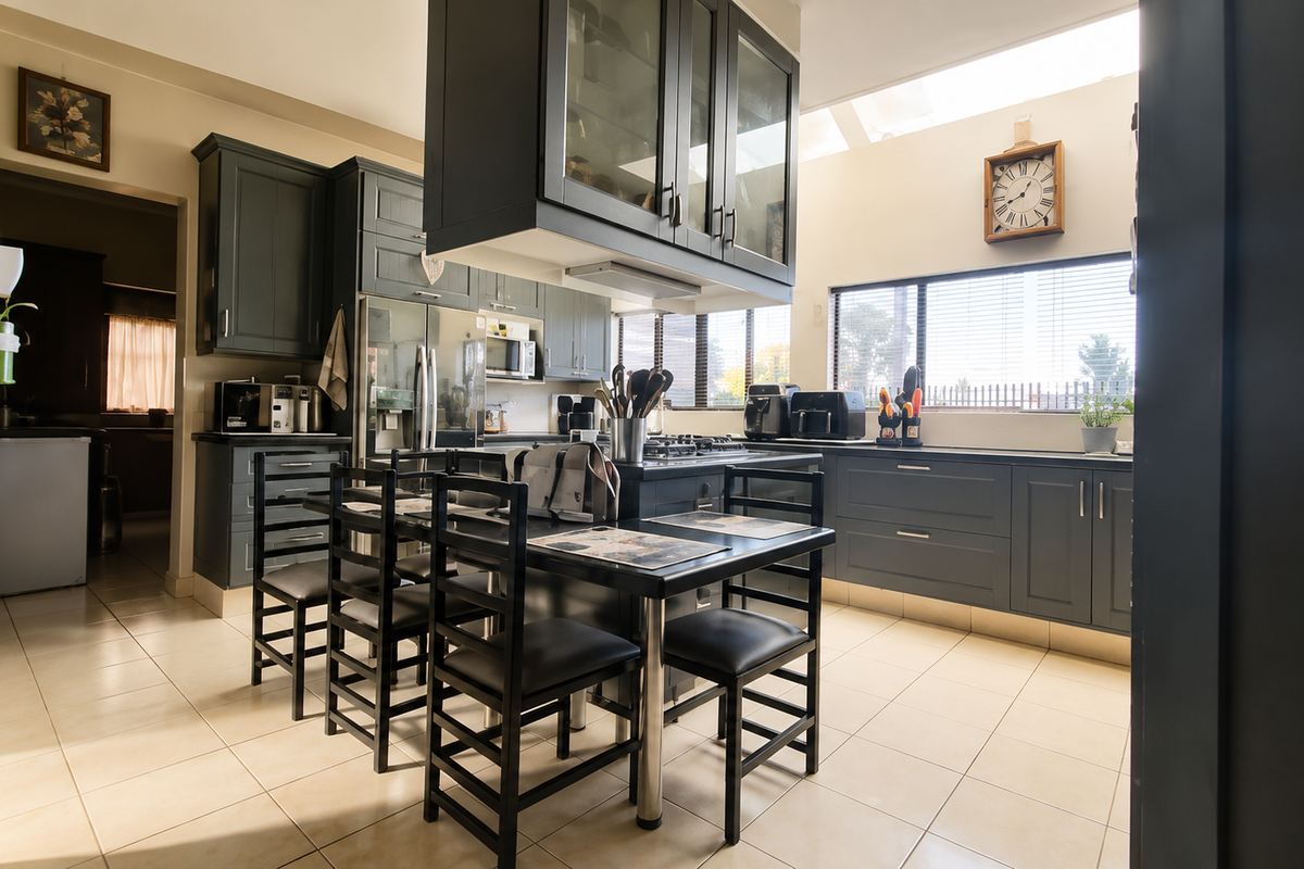 A well-appointed kitchen featuring dark cabinetry, a central island with a gas hob, tiled flooring, and a skylight providing ample natural light.