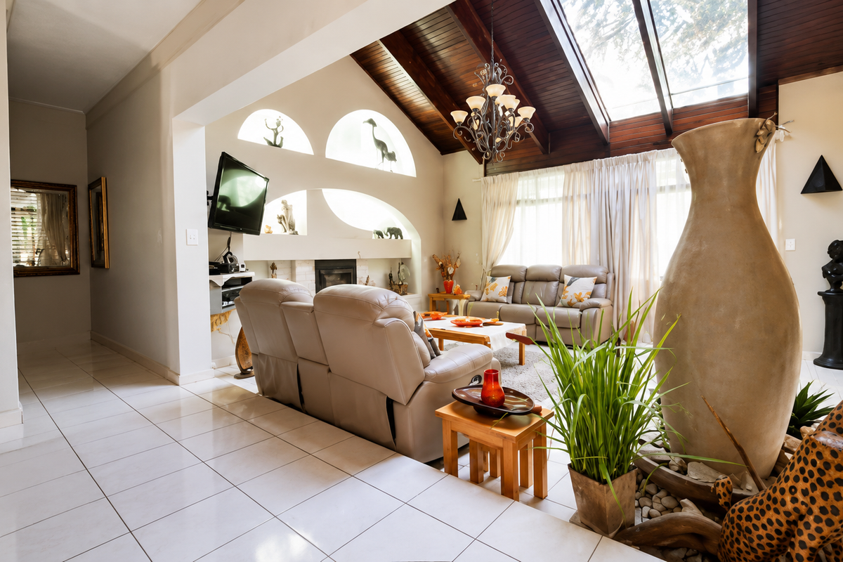 Spacious living room featuring a dramatic vaulted timber ceiling with skylights, tiled flooring, and a built-in fireplace with decorative arched wall niches.