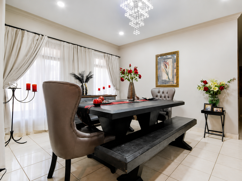 A well-maintained dining room featuring elegant crown molding, polished tiled flooring, and a sophisticated crystal chandelier, creating a bright and inviting atmosphere.
