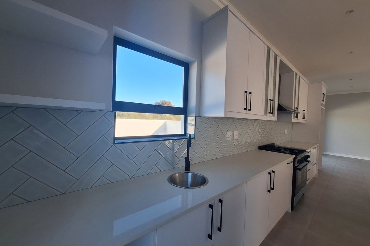 Modern kitchen featuring white cabinetry, stone countertops, a herringbone tile backsplash, integrated sink, and a built-in gas stove with extractor fan.