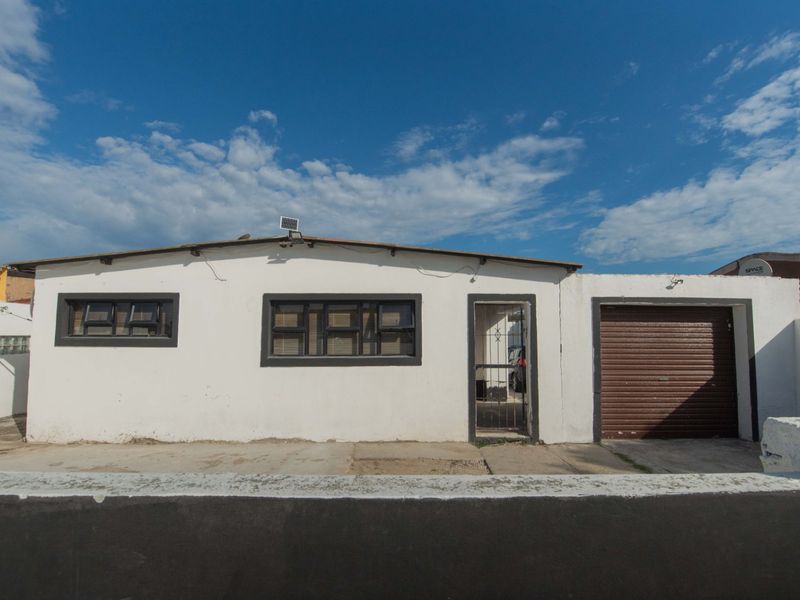 Front elevation of a single-story house featuring a roller garage door, security gate, and aluminium window frames.