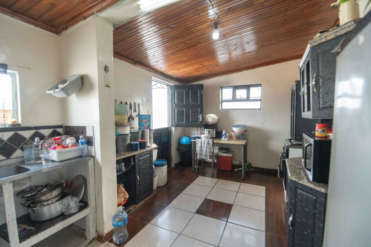 A functional kitchen featuring dark cabinetry, tiled flooring, and a timber-clad ceiling, offering potential for modernization and layout optimization.