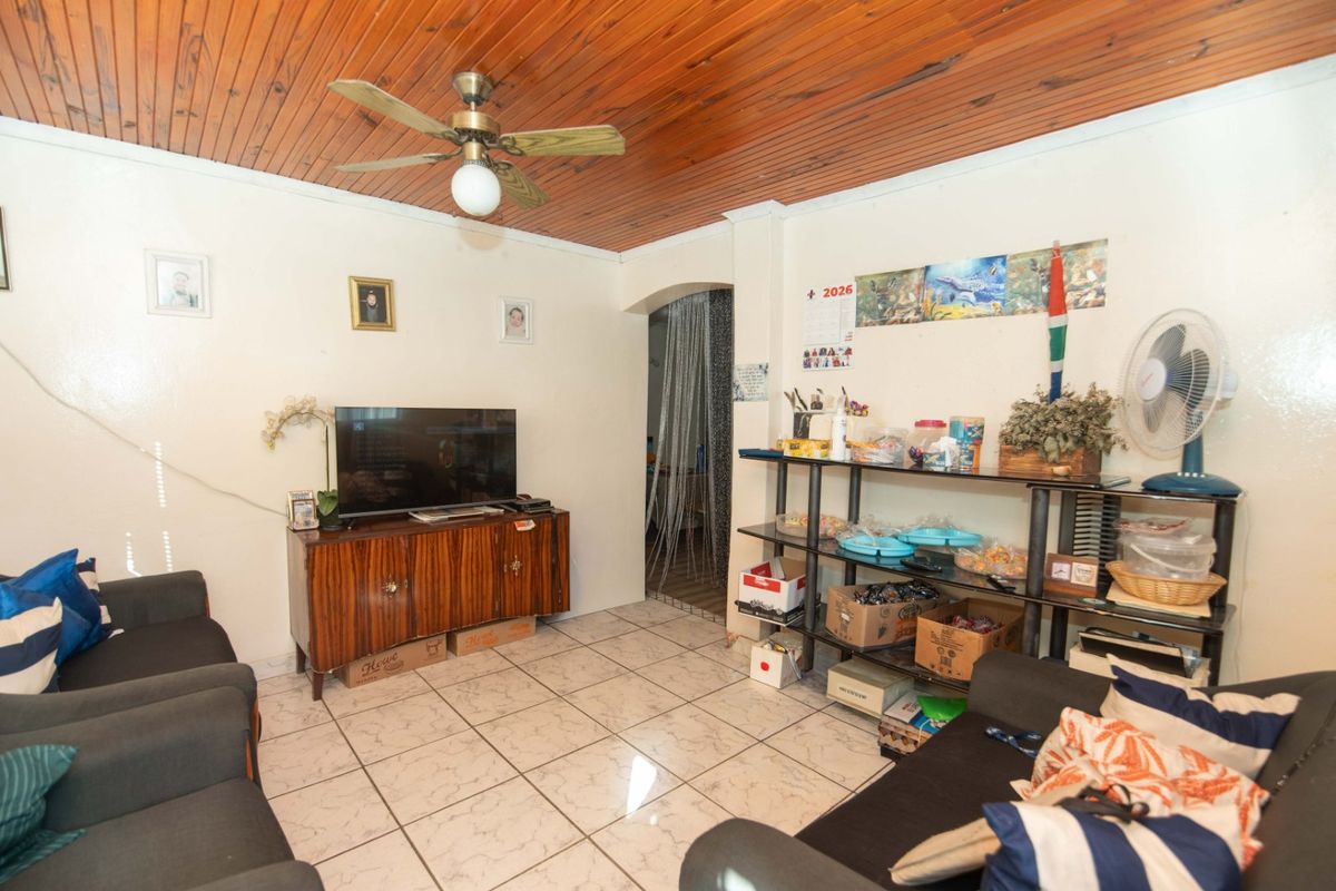 A living room featuring a timber tongue and groove ceiling, ceiling fan, and ceramic tiled flooring with an arched entryway.