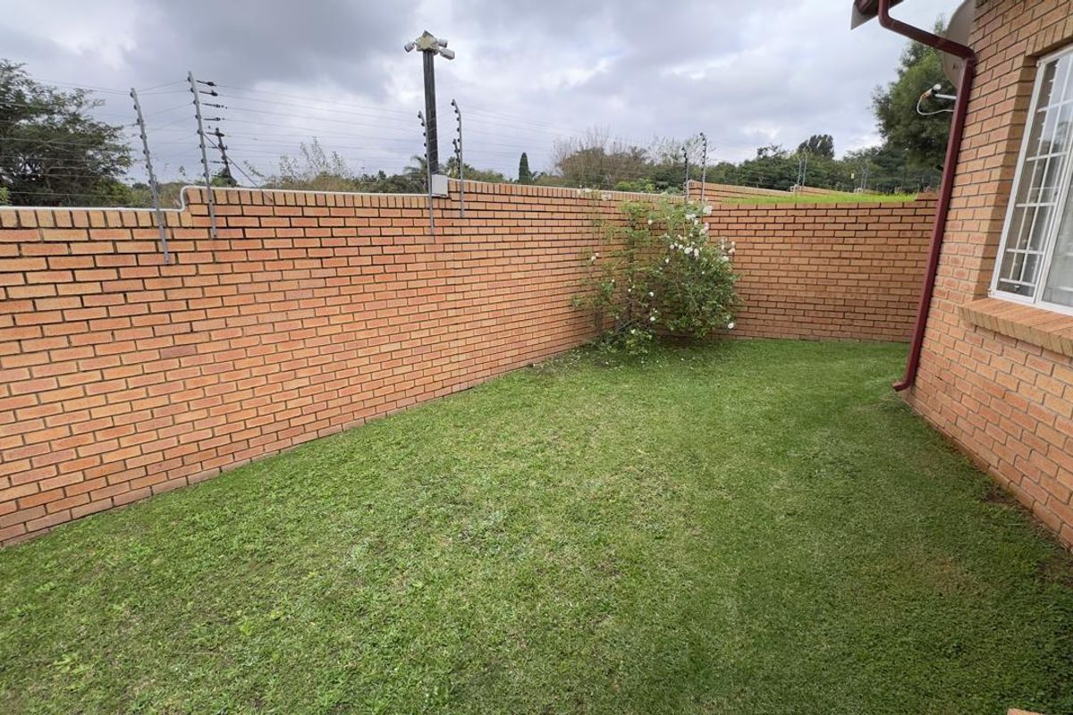 A private rear garden area featuring a brick boundary wall with integrated electric fencing and a small lawn space.