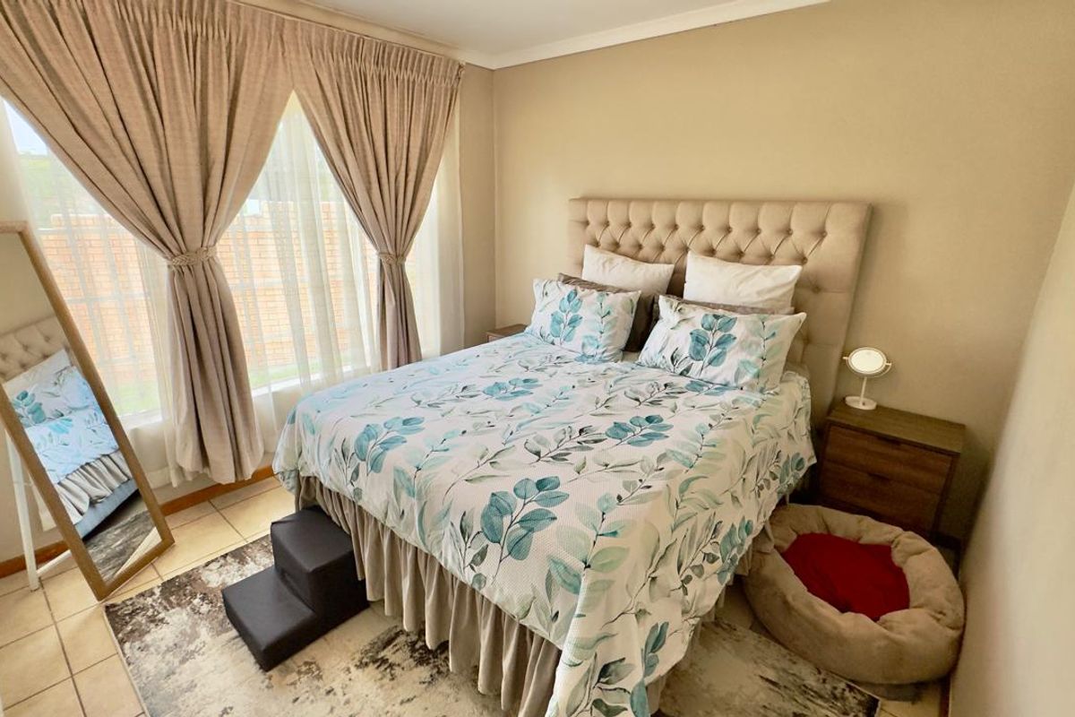 A well-maintained bedroom featuring tiled flooring, neutral wall tones, and large windows that provide ample natural light.