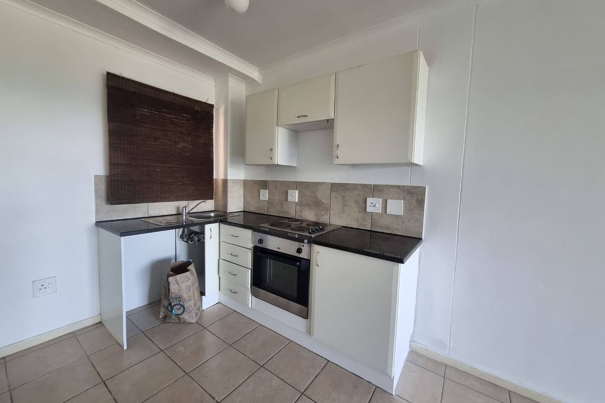 A compact kitchen featuring built-in cabinetry, a tiled backsplash, and integrated oven and hob. The space is functional but requires minor repairs to cabinetry.
